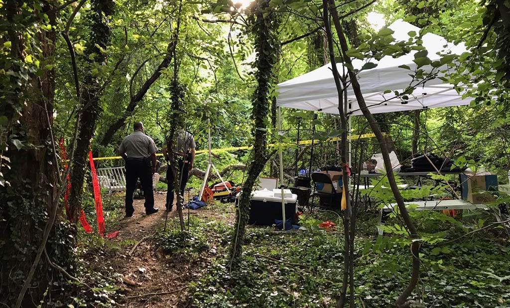Two officers standing near a tent in the woods