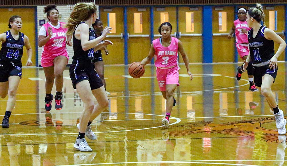 Dunham dribbling upcourt, with defenders on each side of her