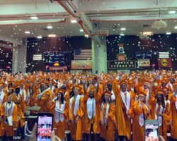 Hayfield seniors throwing hats in the air in 2019 graduation ceremony in school gym