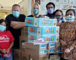 Seven people wearing masks posing with boxes of food