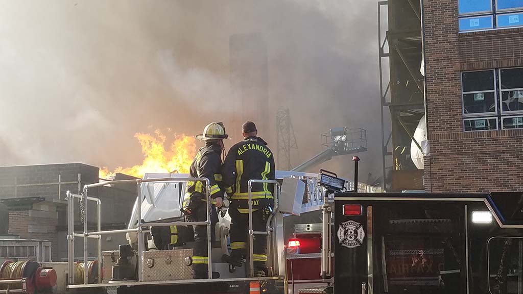 Firefighters on top of truck in front of fire