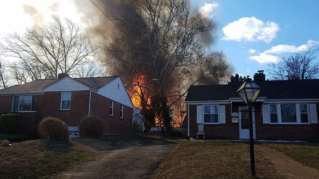 Bright orange fire between two brick homes. 