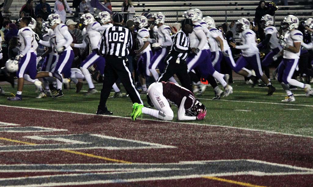 Lake Braddock players running by a Mount Vernon player with his head down