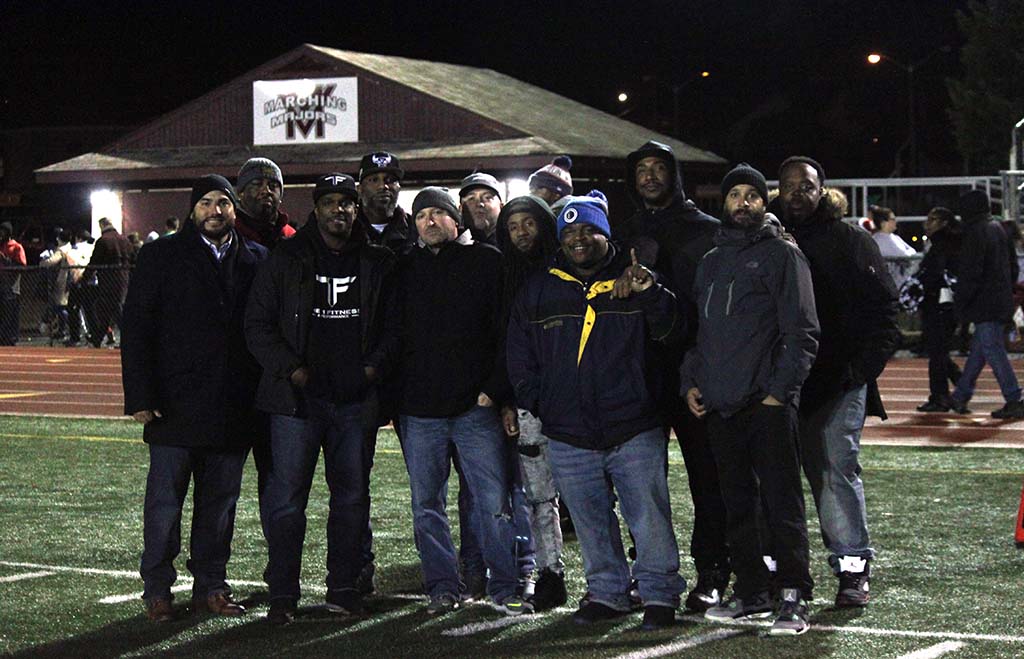 Group of men posing for picture on the sideline
