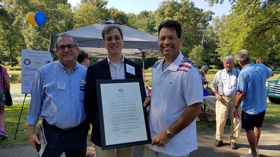 Trio posing for image holding framed proclamation 