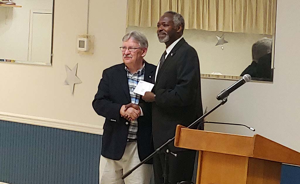 Coleman and Spychaj shaking hands and holding award